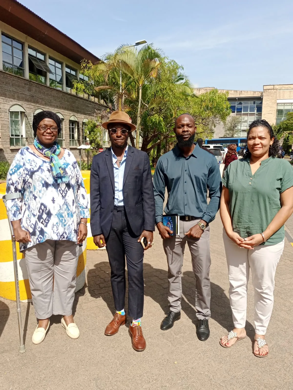 Four people standing together outside an institutional building