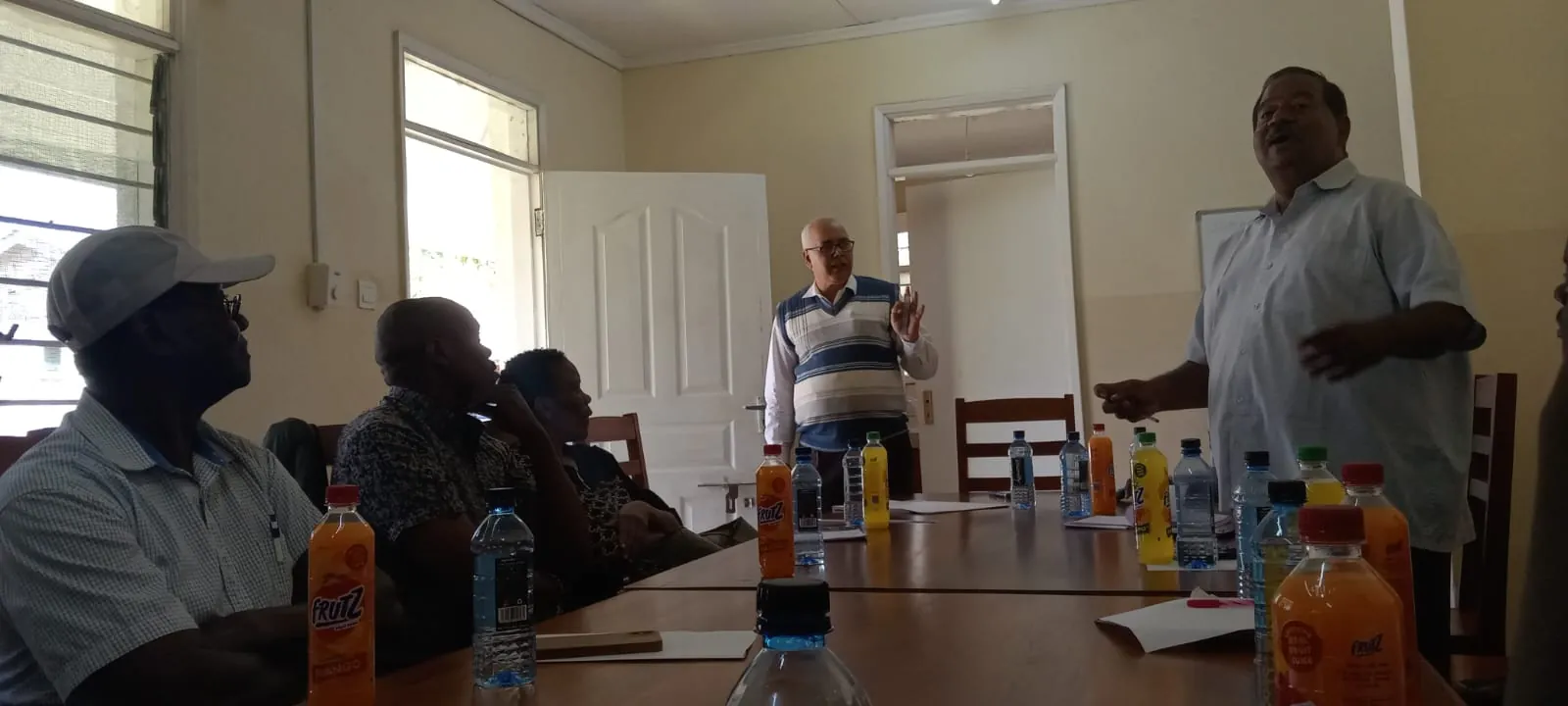 A man addressing a seated group in a meeting hall
